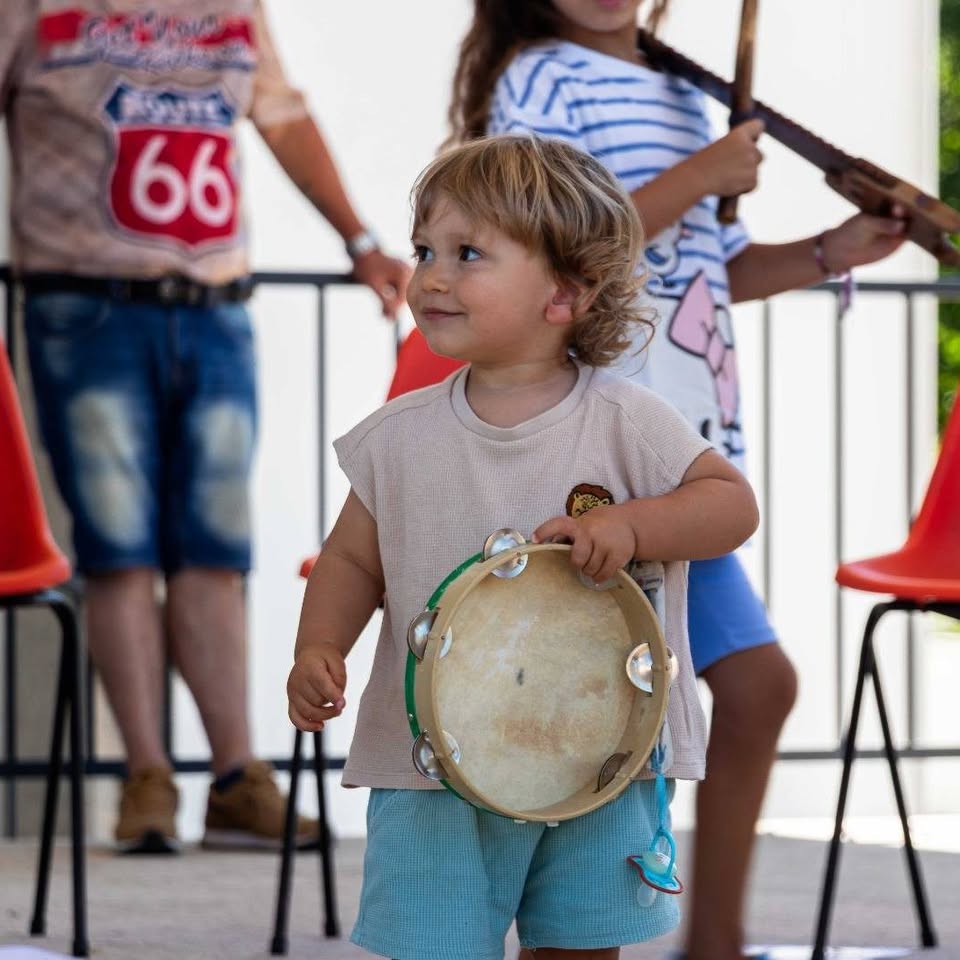Criança a descobrir um instrumento tradicional numa atividade da associação